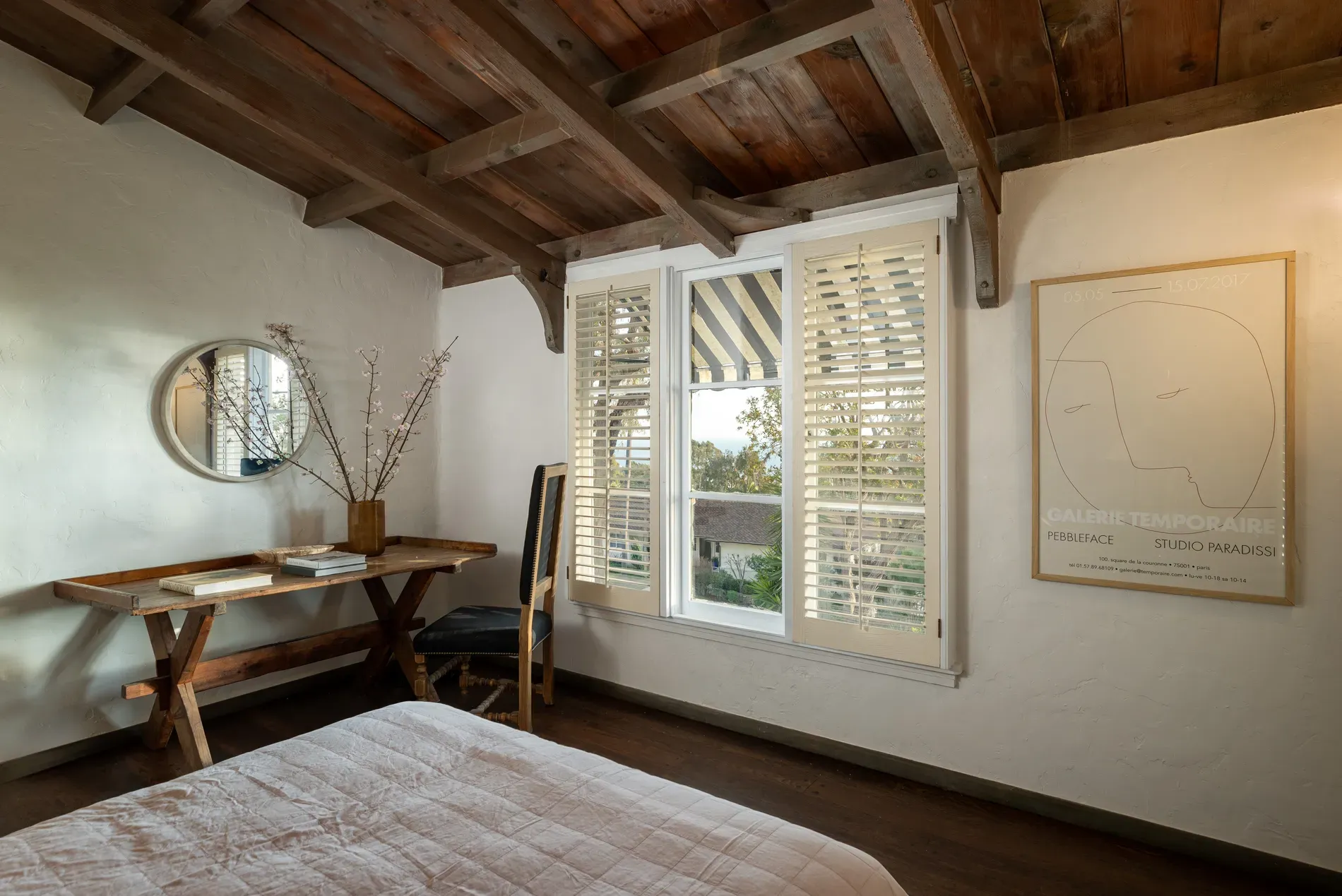 Here's the bedroom — sloped wood ceiling, chunky beams, calm whites.