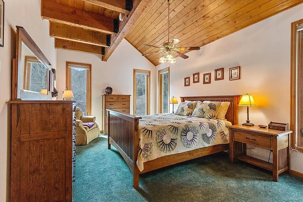 Okay, this bedroom nails the cabin vibe—beams up top, super cozy.