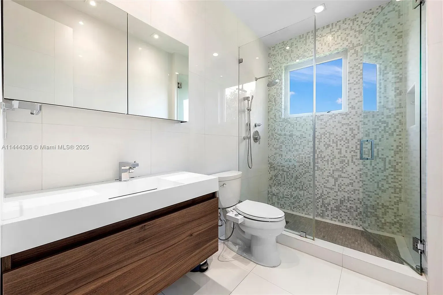 Here’s the bath — white tile everywhere, huge shower, glass so clean it disappears.