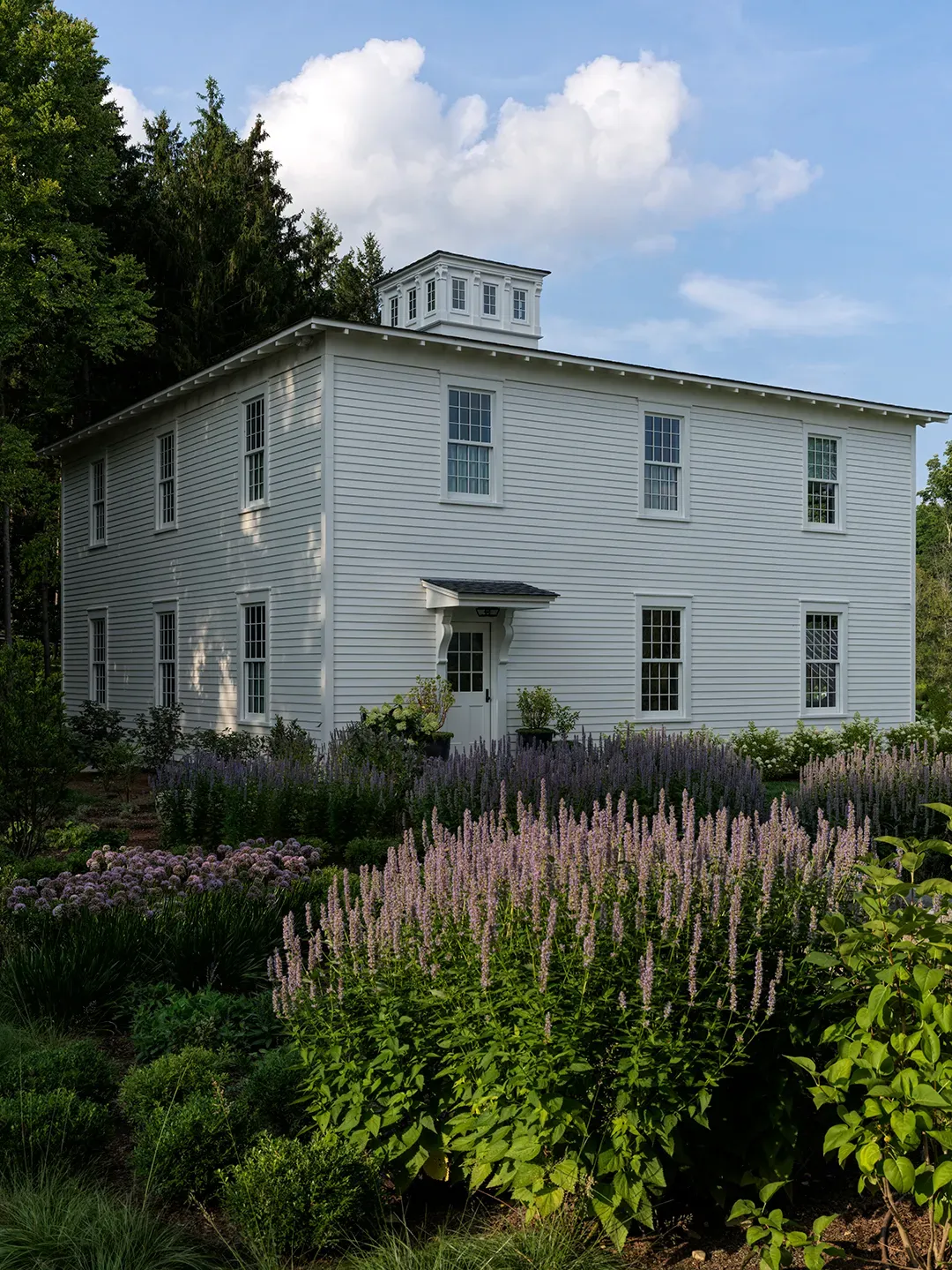 Here's the exterior—white clapboard, big windows, cupola flex. From the street, timeless.