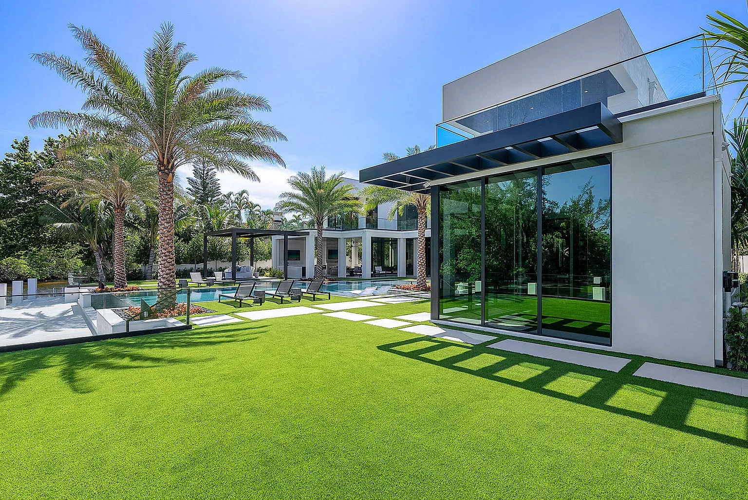 Back outside—turf lawn, black loungers, clean lines. Not mad at it.