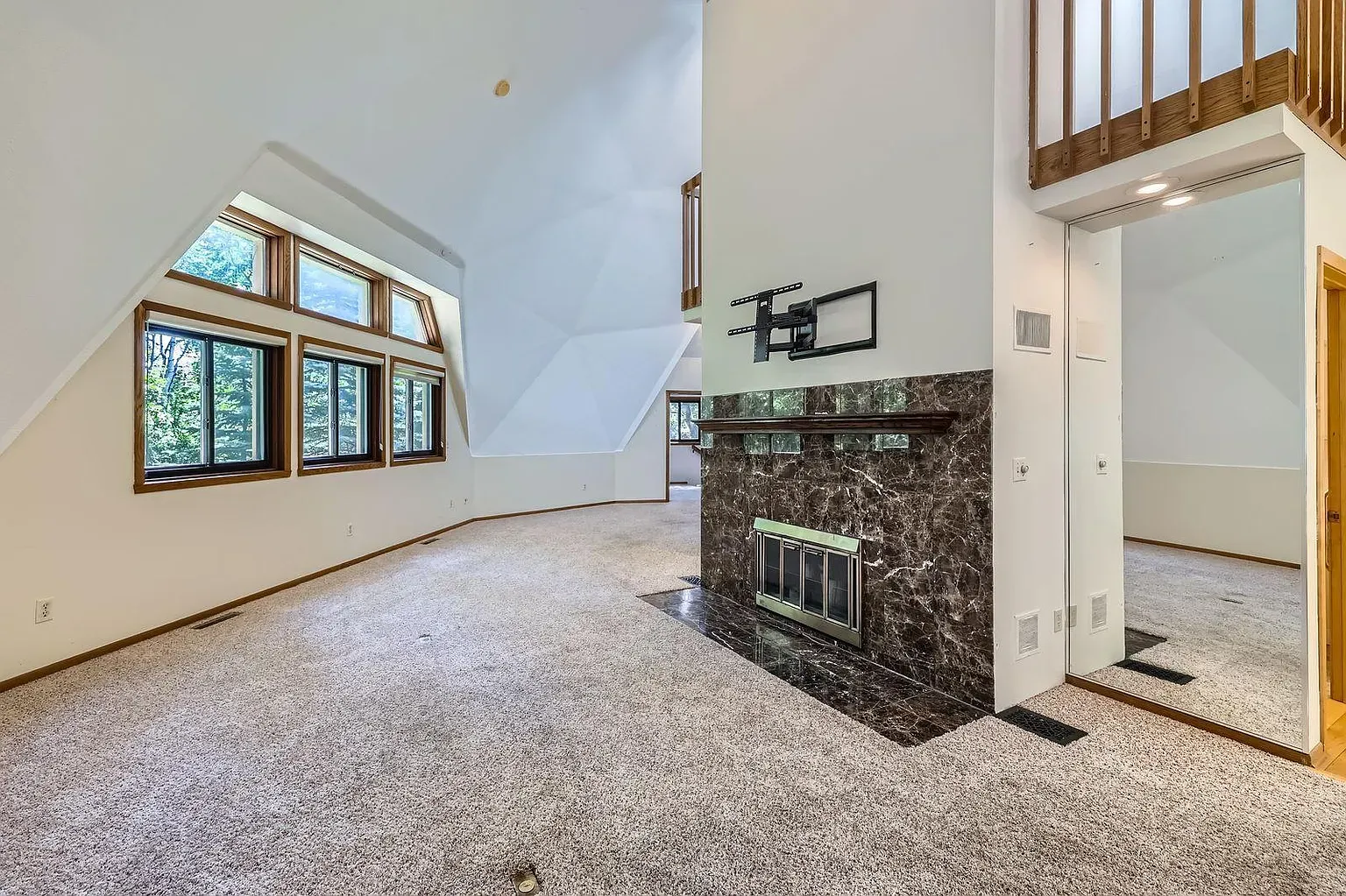 Slanted-ceiling living area—white walls, beige carpet. Not sure about this combo.