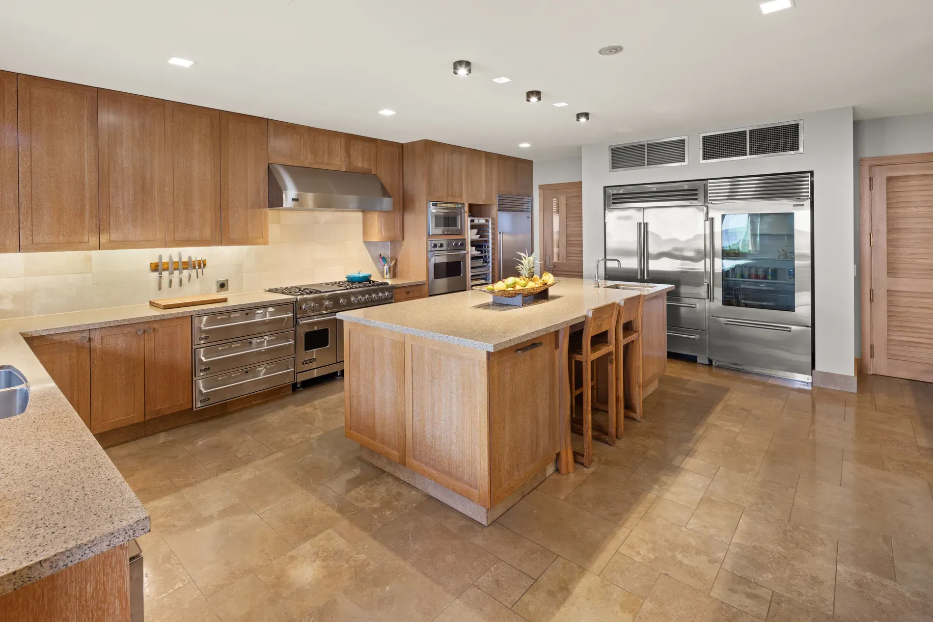 Kitchen is warm wood and stone. clean lines, no handles, very sleek.