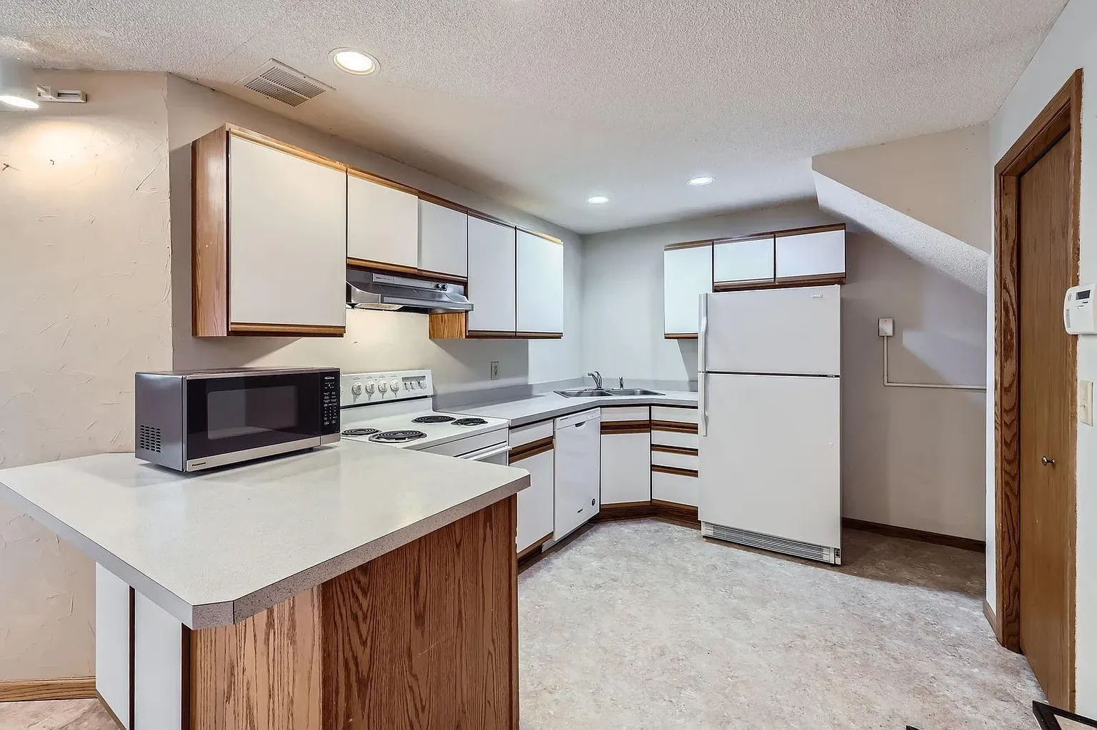 Here's the U-shaped kitchen. beige walls, white cabinets, everything reachable. Efficient.