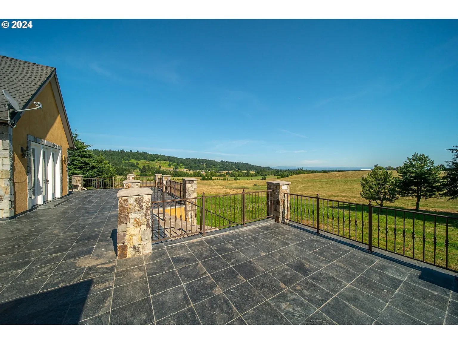 Terrace is huge—slate floor, chunky stone pillars, iron rail. Views go forever.