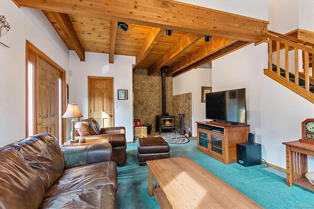 Wide shot of the living room—wood ceiling, beams, big windows. Warm without feeling heavy.