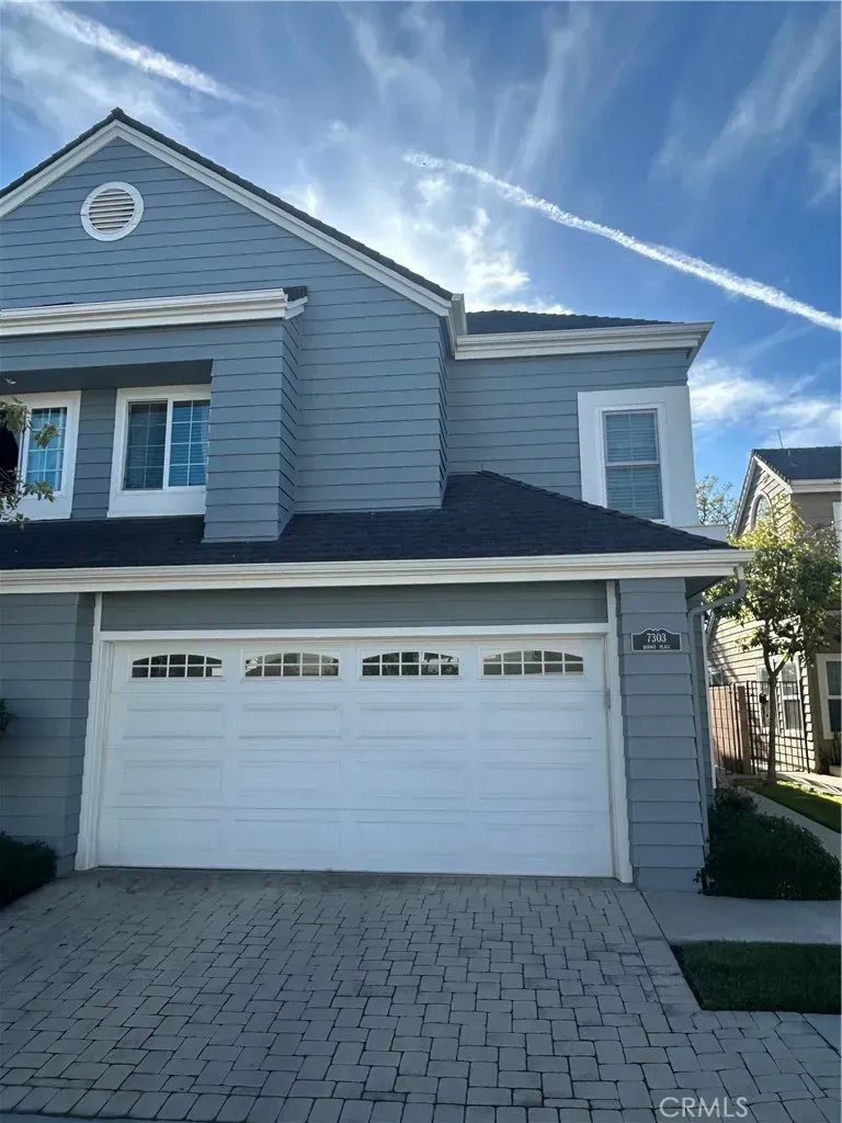 Back outside. light blue siding, double garage. Round window staring from this angle—why?