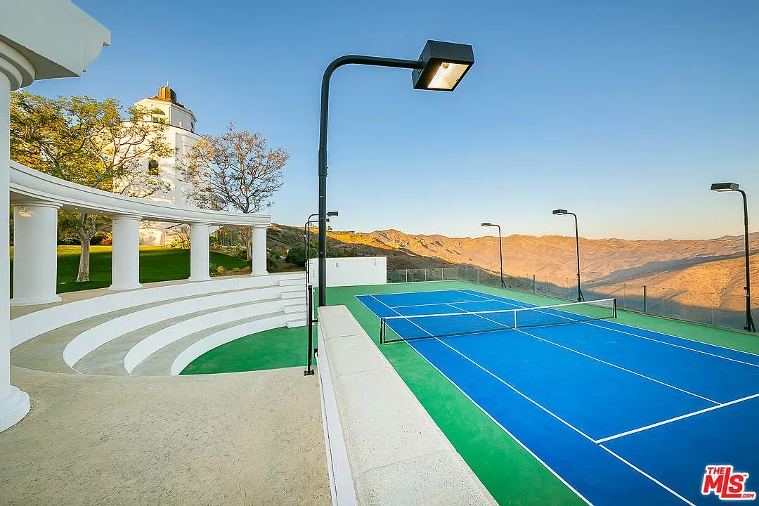 Tennis court goes bright blue. Seating pavilion looks fancy. Windy here, maybe?