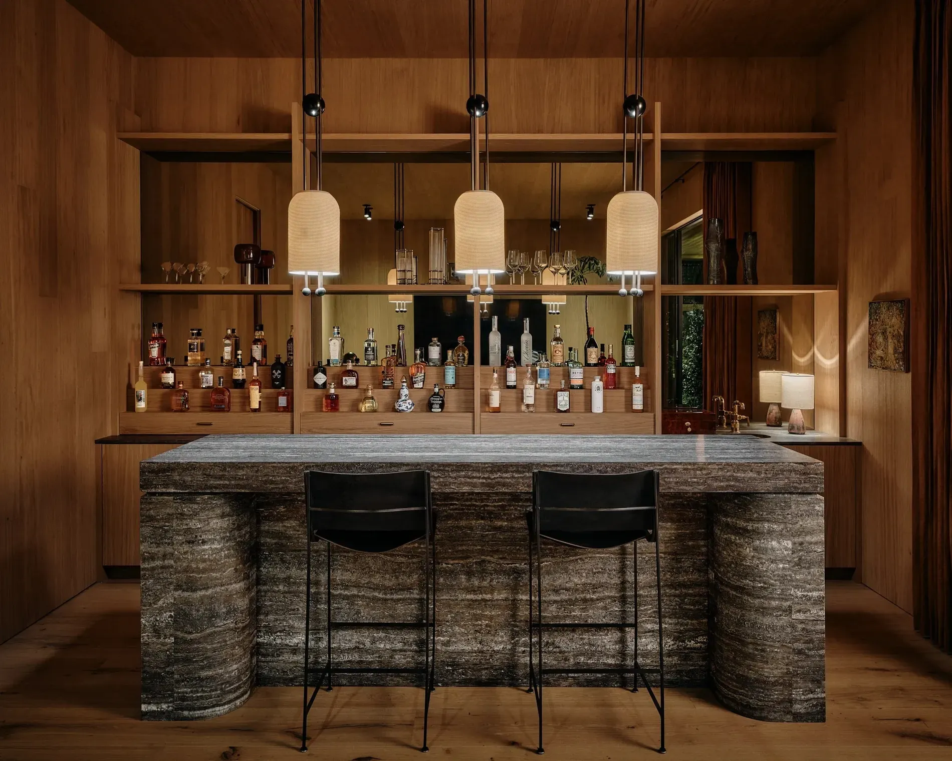 Home bar tucked in wood paneling. That brass rail? Dangerous in the best way.