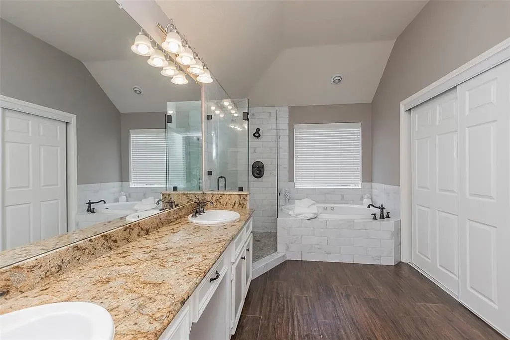 Big airy bathroom with the sloped ceiling. Calm grays and warm wood vanity.