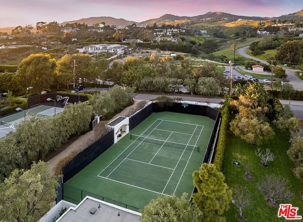 Tennis court tucked in green hills. Anyone know why the fence is that high?
