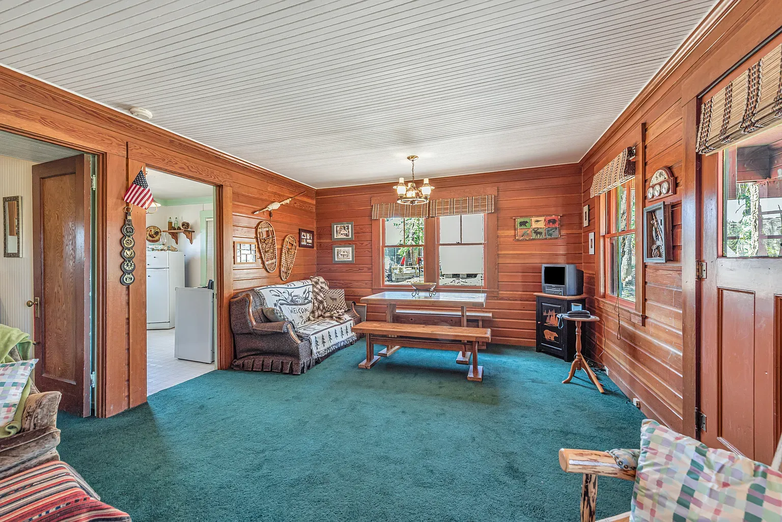 Living room goes full cabin. chestnut walls, green carpet, super inviting.