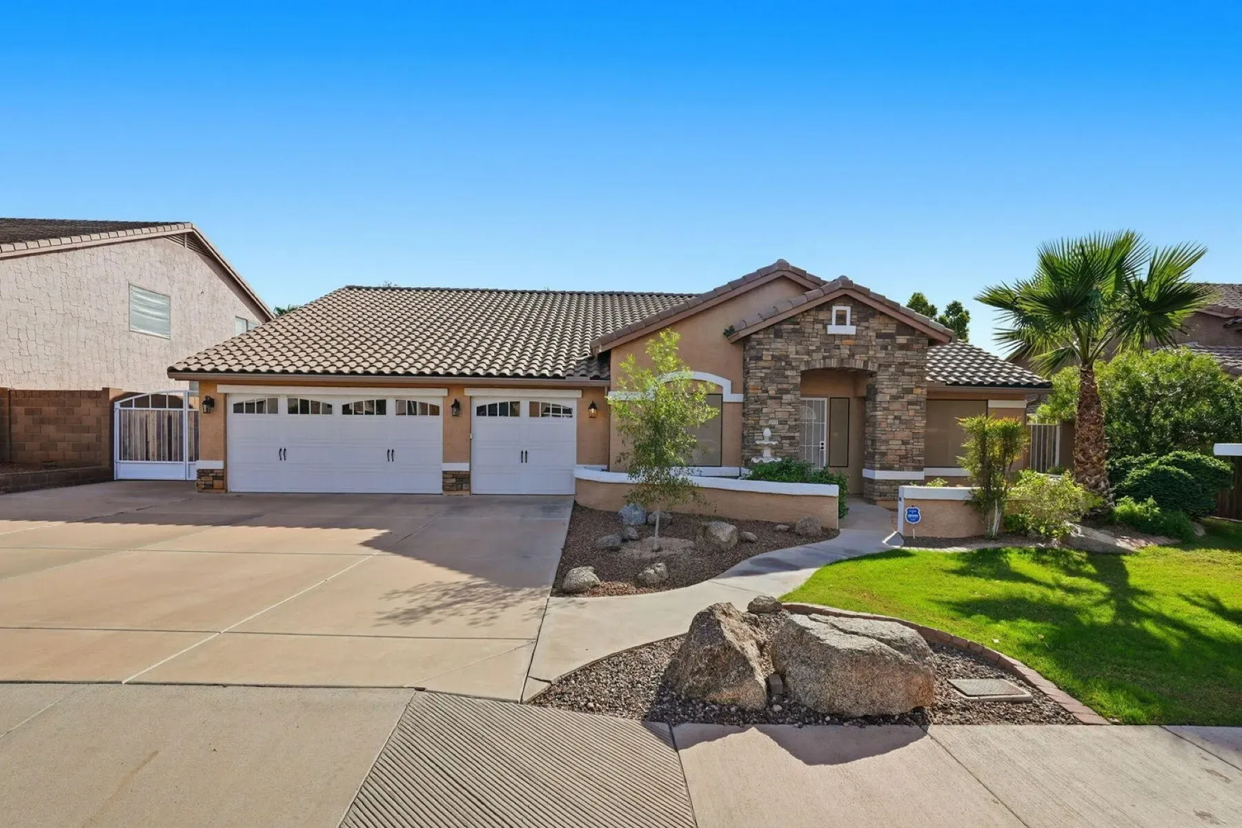 Single-story Mediterranean front—stucco, stone, tidy landscaping. Cute and low-key.