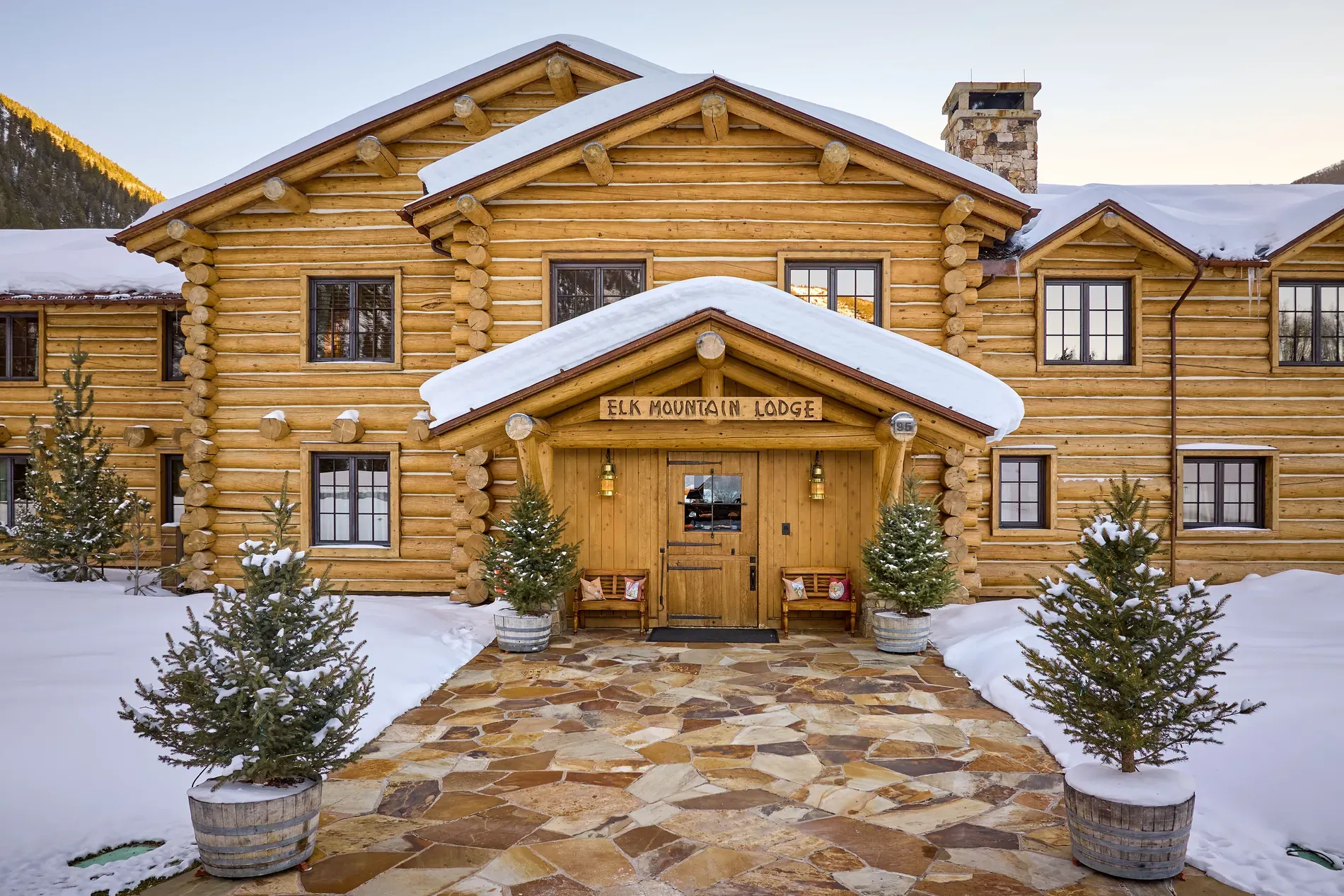 Here's the front — massive round logs, snow dusted, very postcard mountain vibes.
