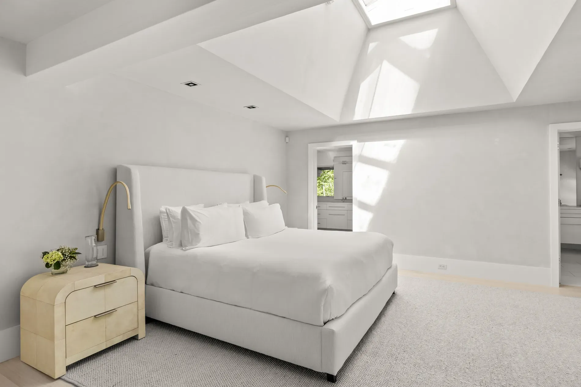 Bedroom goes full cloud. Upholstered headboard, light wood nightstand. Simple, calm, nice.