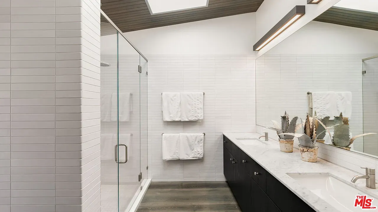 Glossy white tile, dark vanity, big mirror. Feels clean without feeling cold.