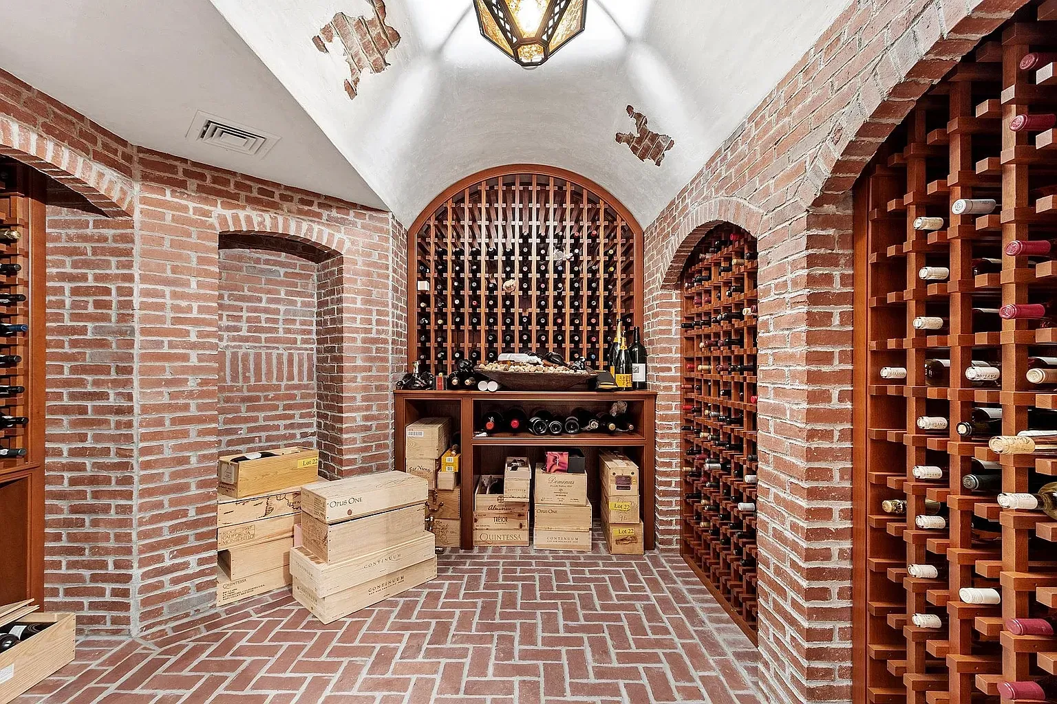Brick wine room with an arched ceiling and a moody lantern.