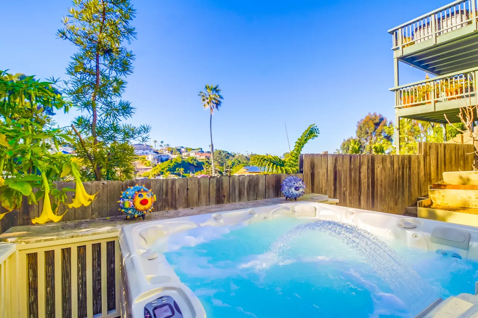 Backyard hot tub tucked behind wood fencing. Yes please.