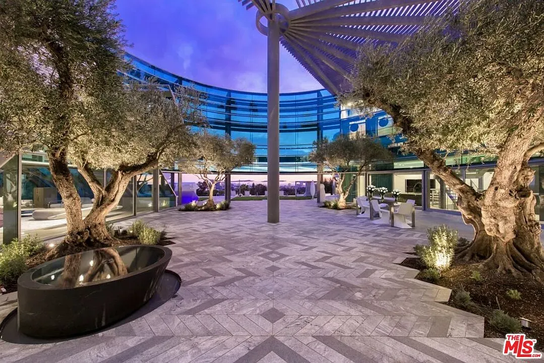 Round courtyard with patterned stone and a slatted pergola. Very calm.