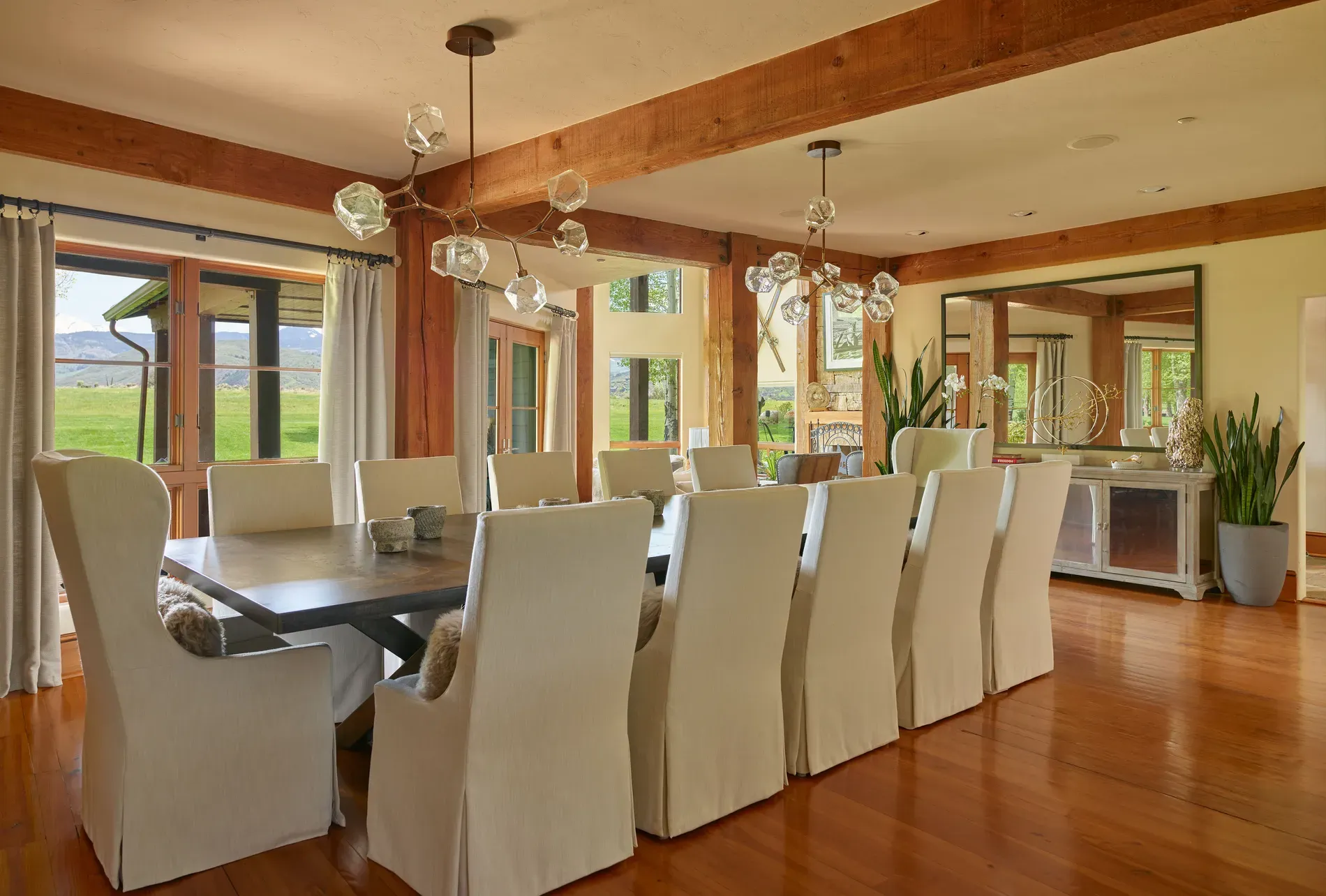 Warm dining space, honey floors and curtain-y windows. Anyone know that chandelier brand?