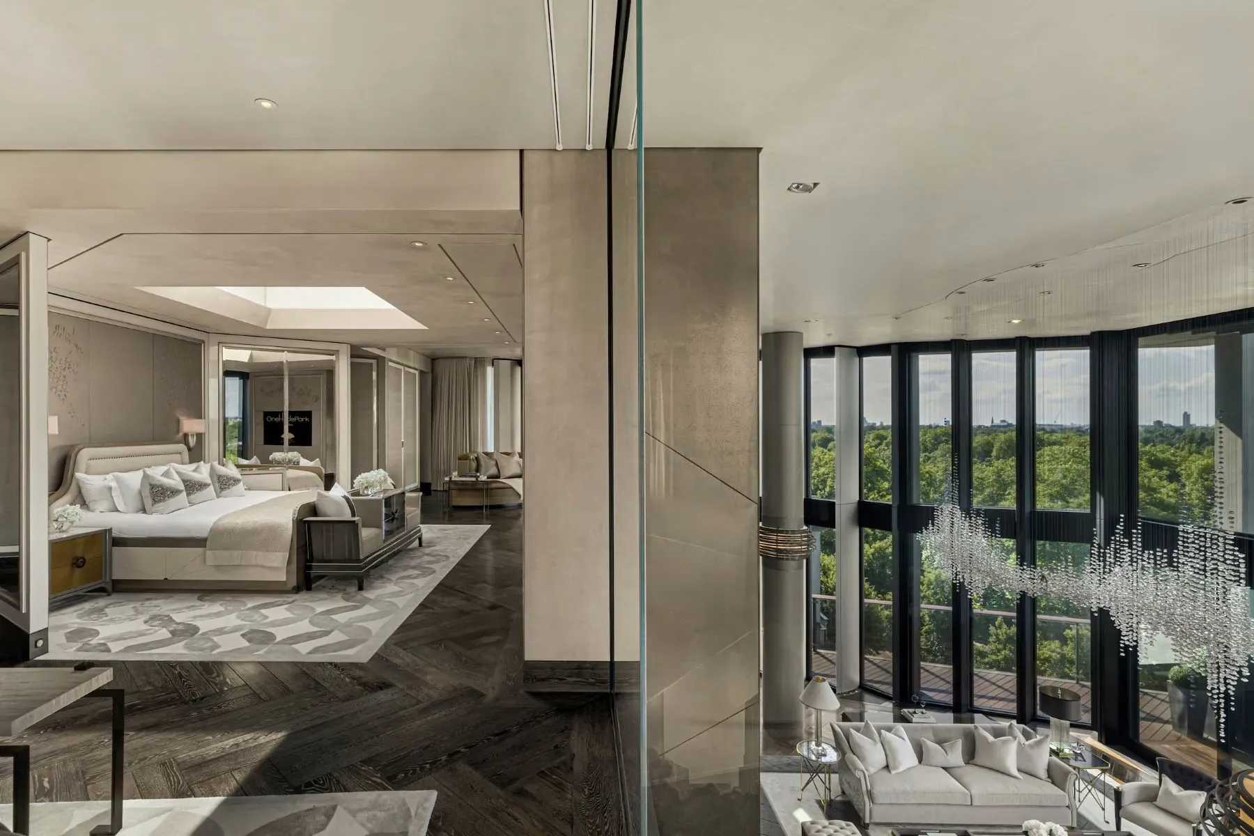 Herringbone floors steal it. Bedroom and lounge blur together behind glass.