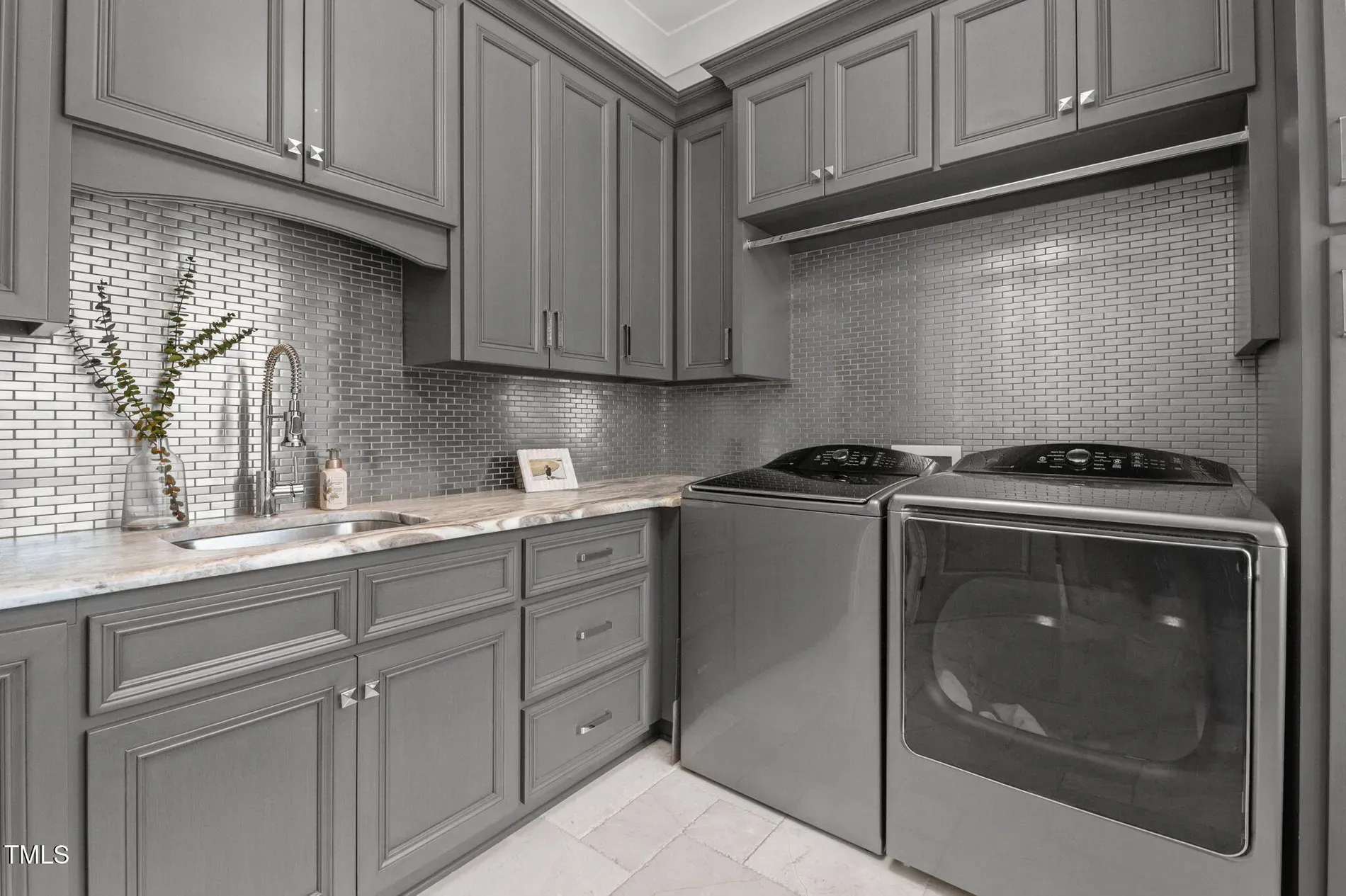 Laundry pretending to be a boutique. Gray cabinets, marble tops—fancy for socks.