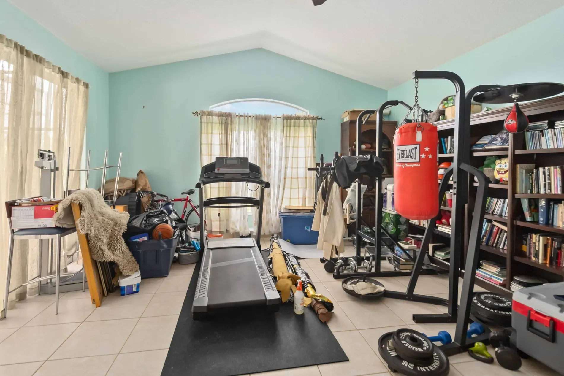 Tall arched window, pale blue walls. Big, airy, currently pretty empty.