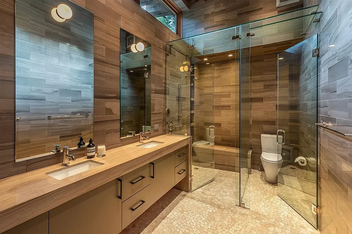 Floor-to-ceiling glass in the bathroom. Wood keeps it warm, not showroom.