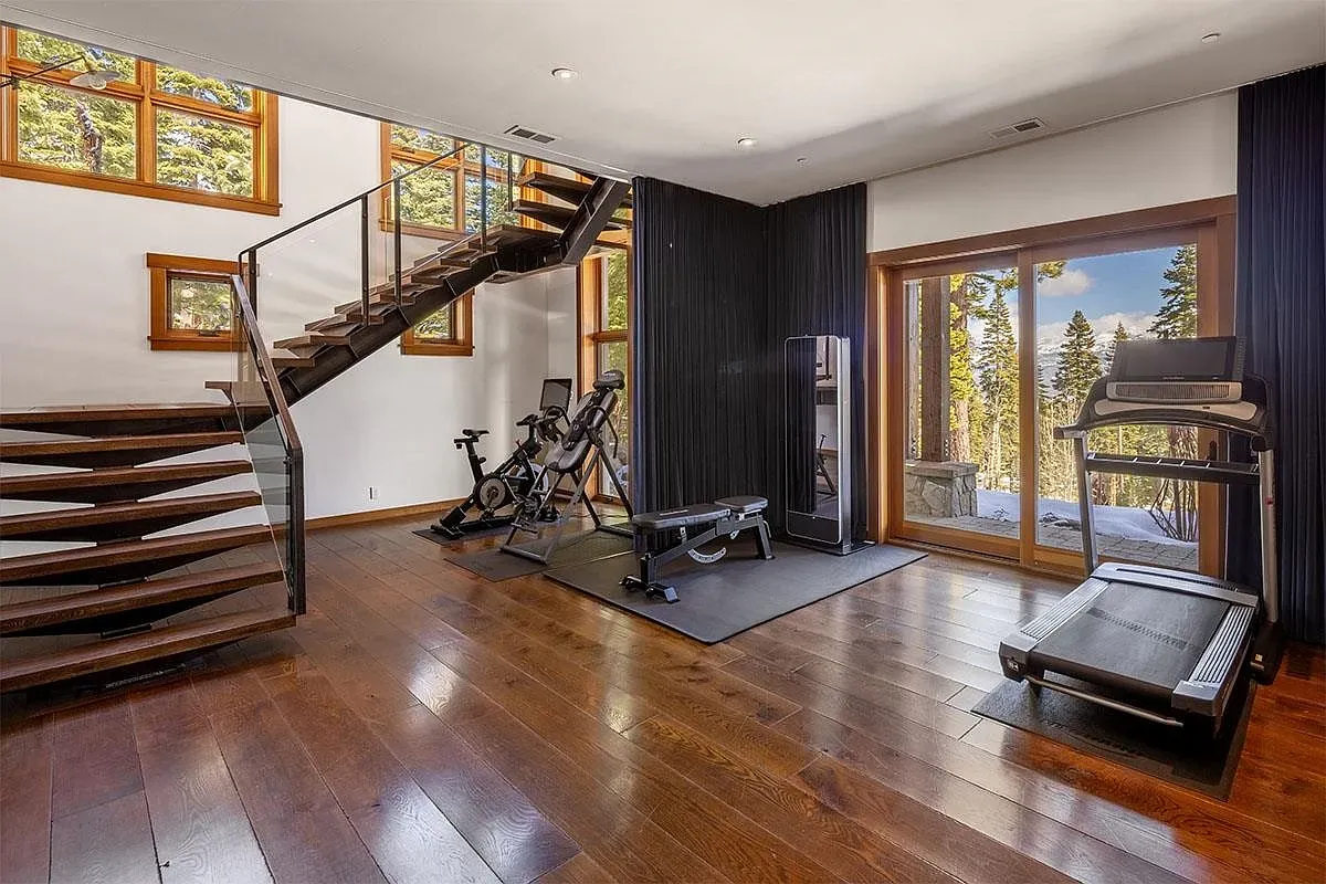 Spiral wooden staircase with glass railing in the gym is wild.