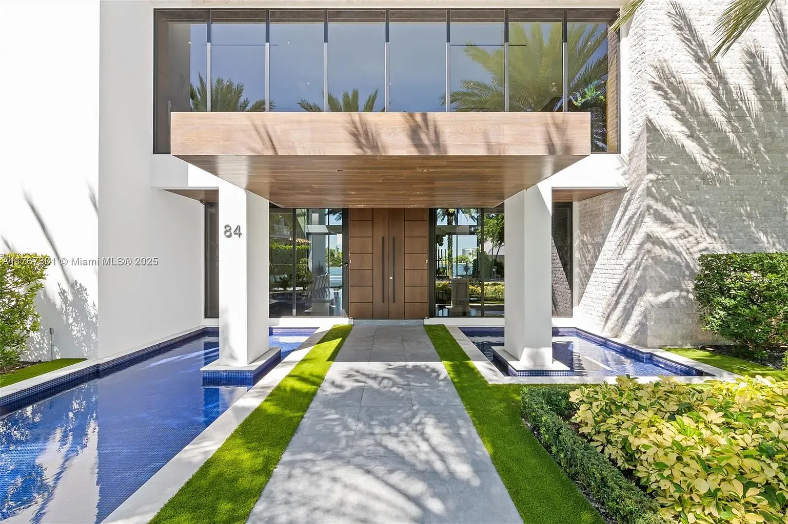 Entry with oversized wood door. Landscaping is tidy and intentional.