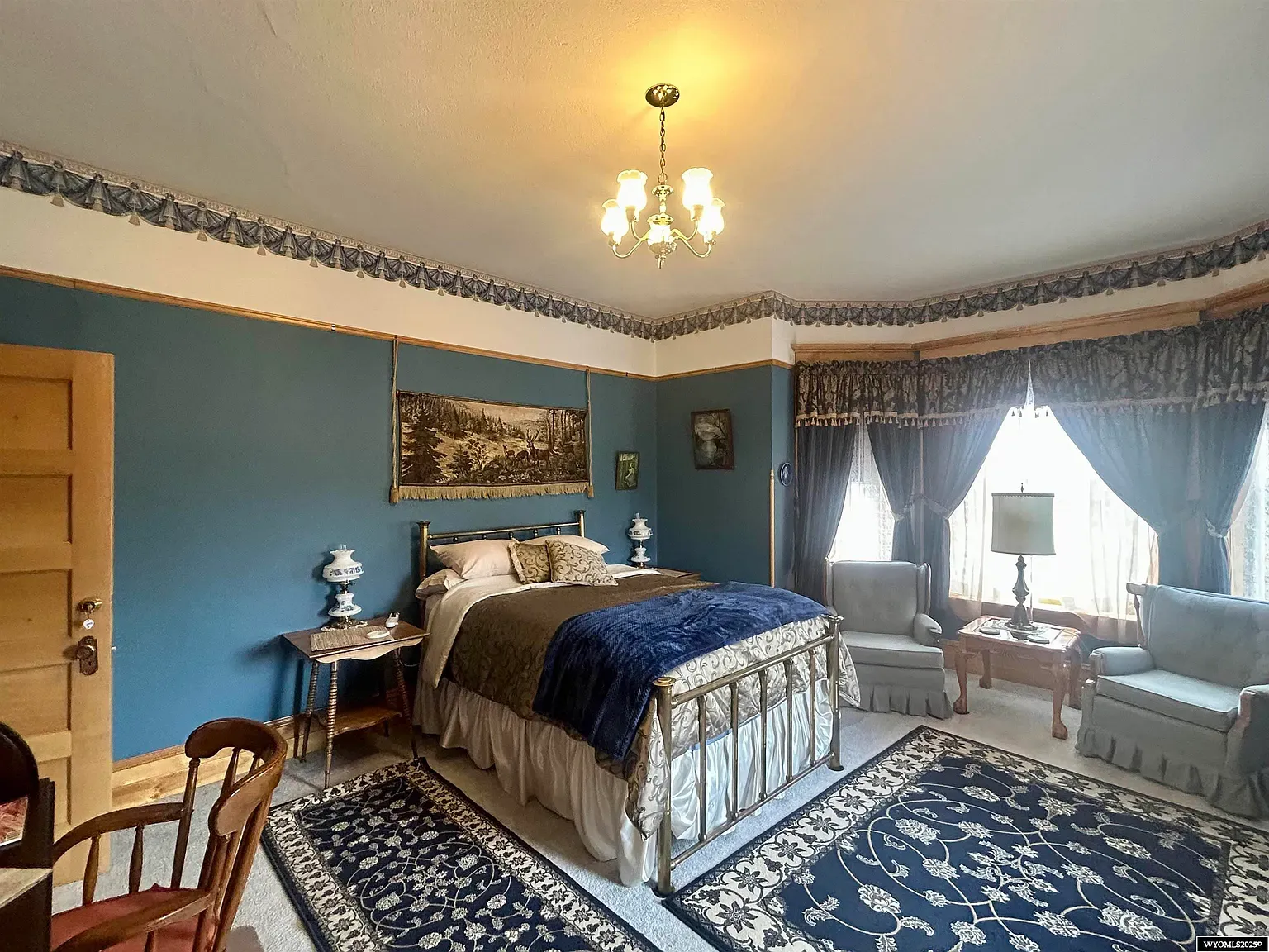 Deep blue bedroom with an ornate metal bed. Looks quiet and hotel-level comfy.