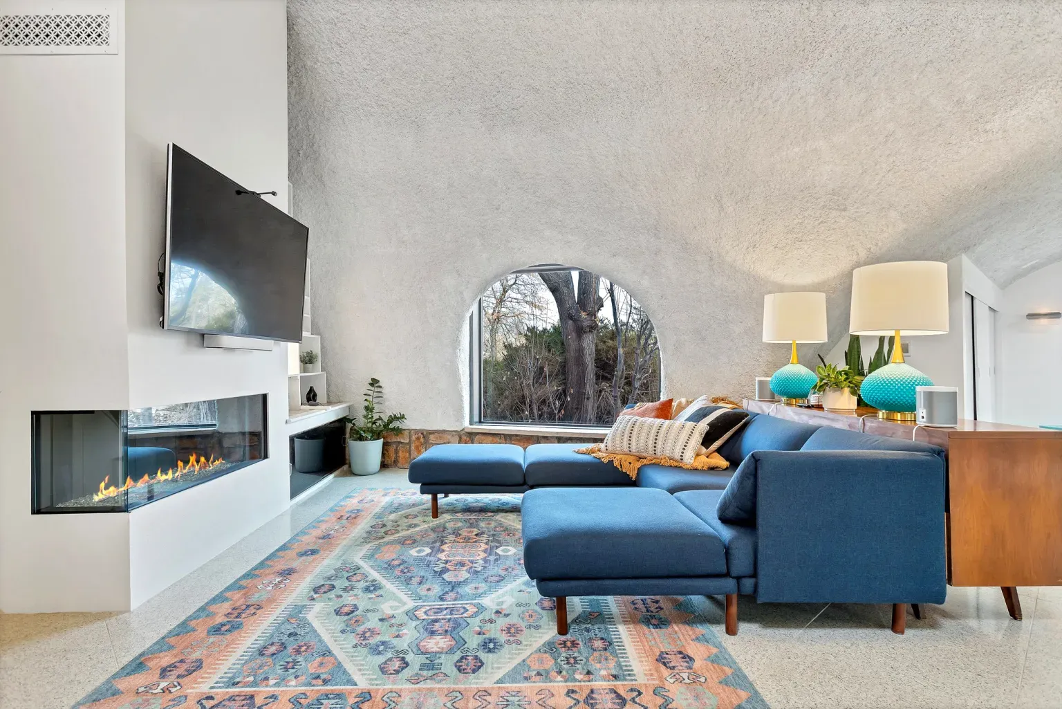 Deep blue sofa anchoring the space, ceiling curves doing the most.