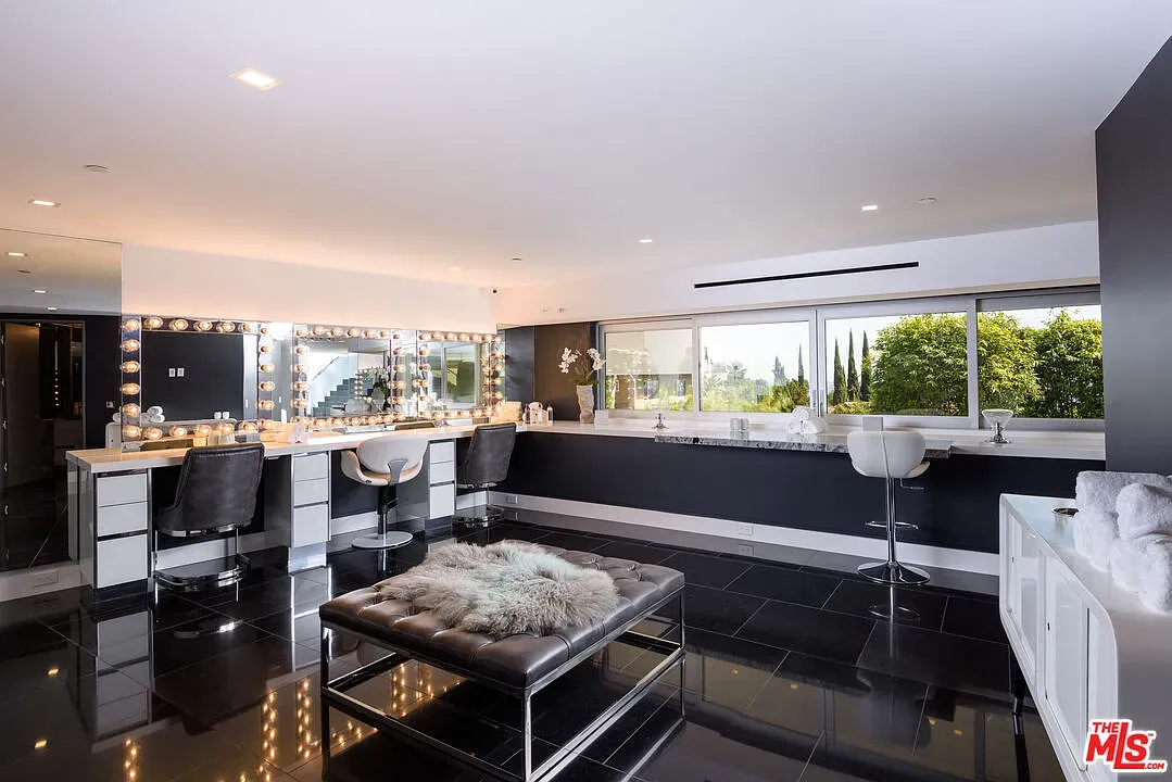 Glam room with glossy black tile and wall-to-wall storage. Massive mirror.