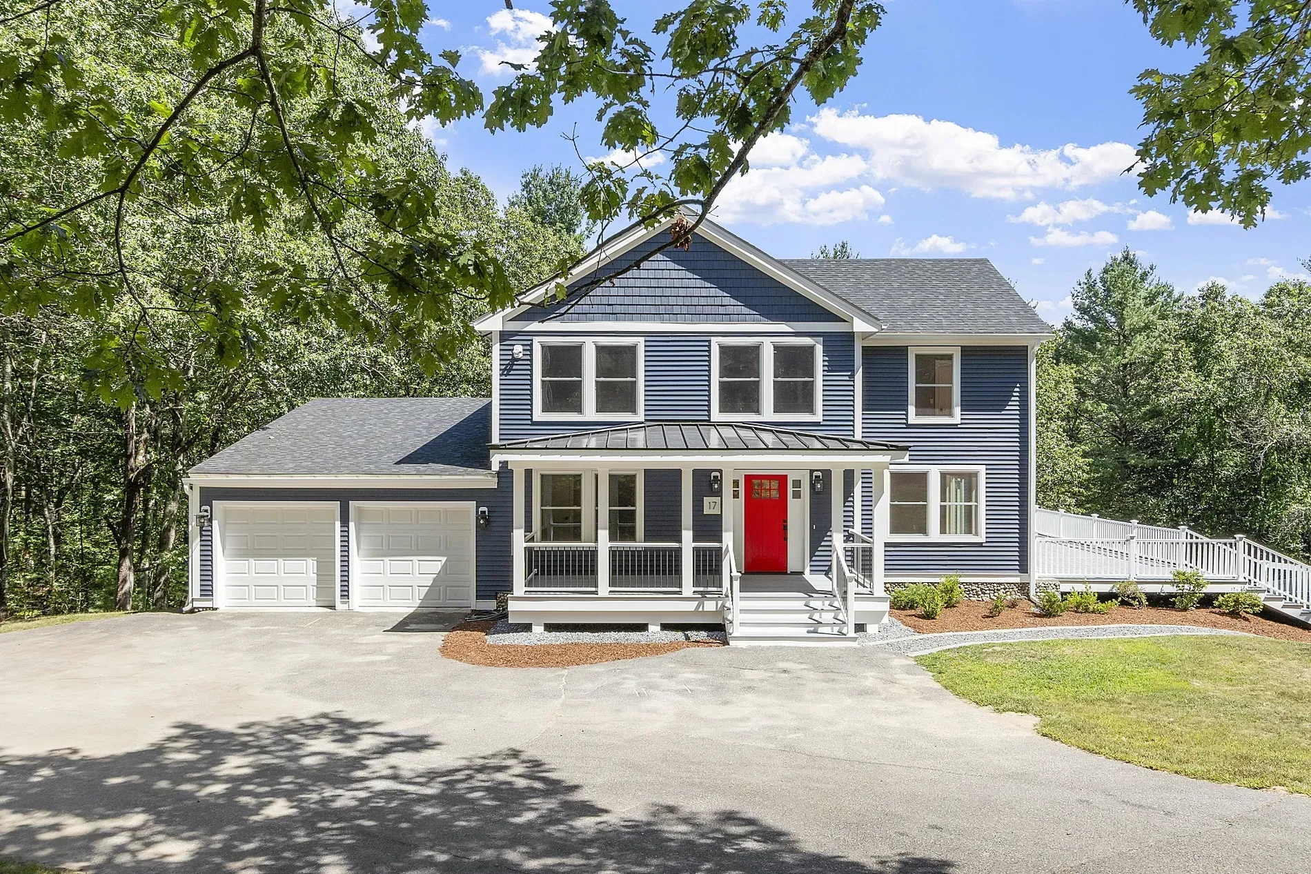 Blue clapboard exterior with a red door, tucked under tall trees.