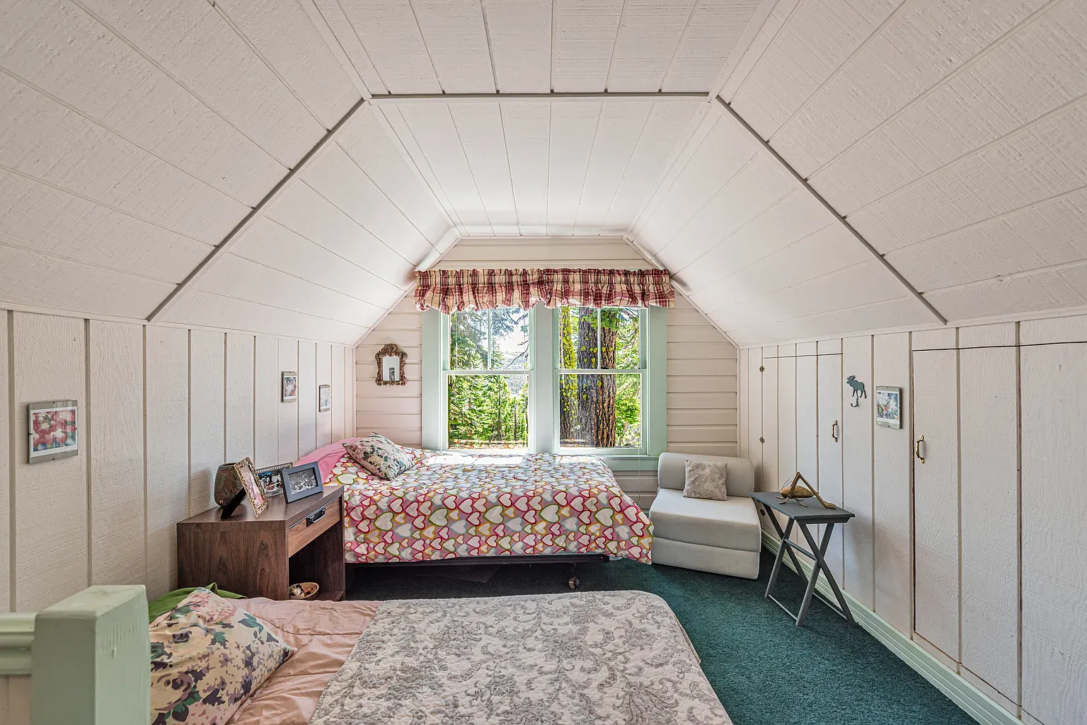 Sloped ceiling bedroom feels snug. White paneling and beige carpet keeping it bright.