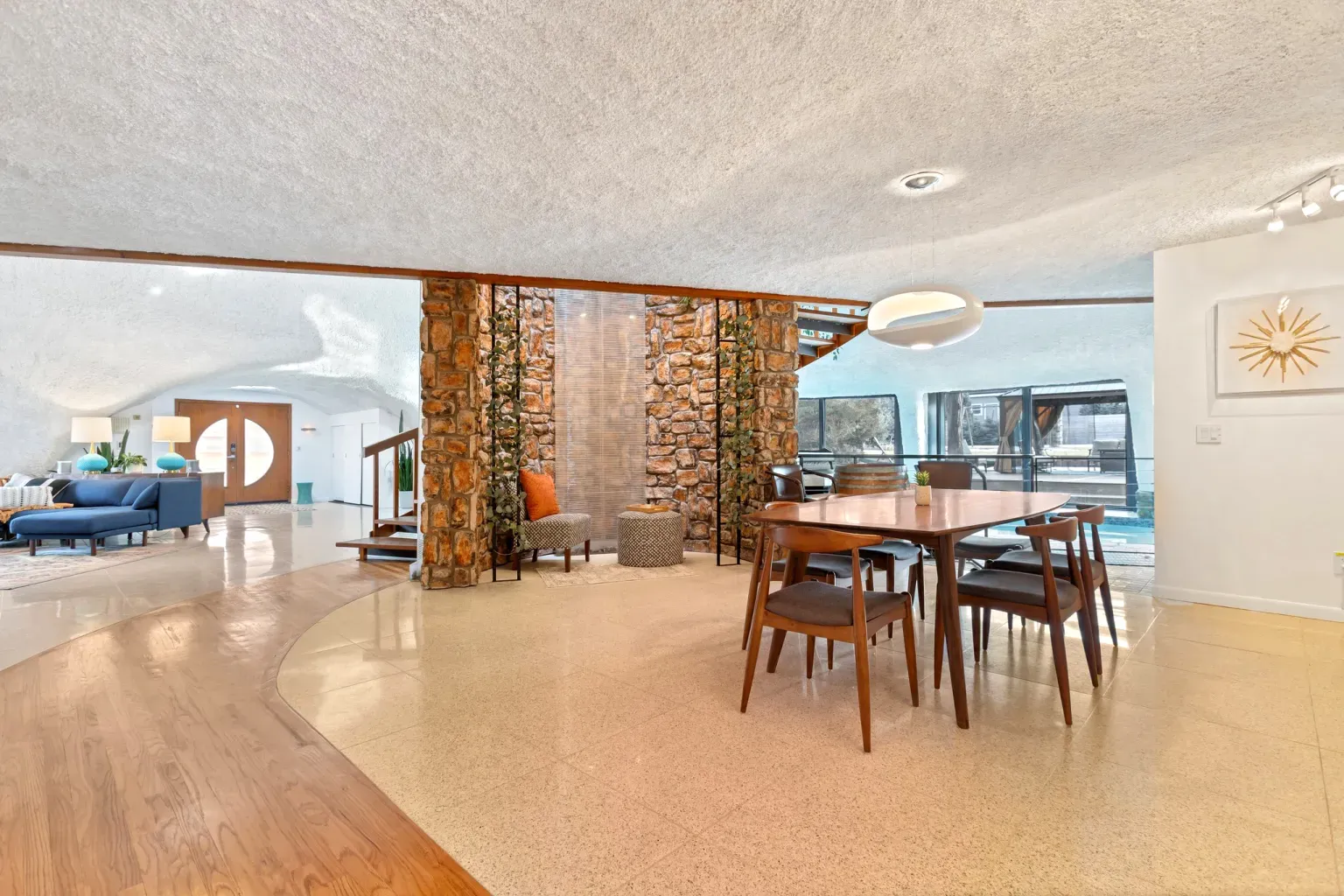 Stone feature wall steals the scene under that soft curved ceiling.