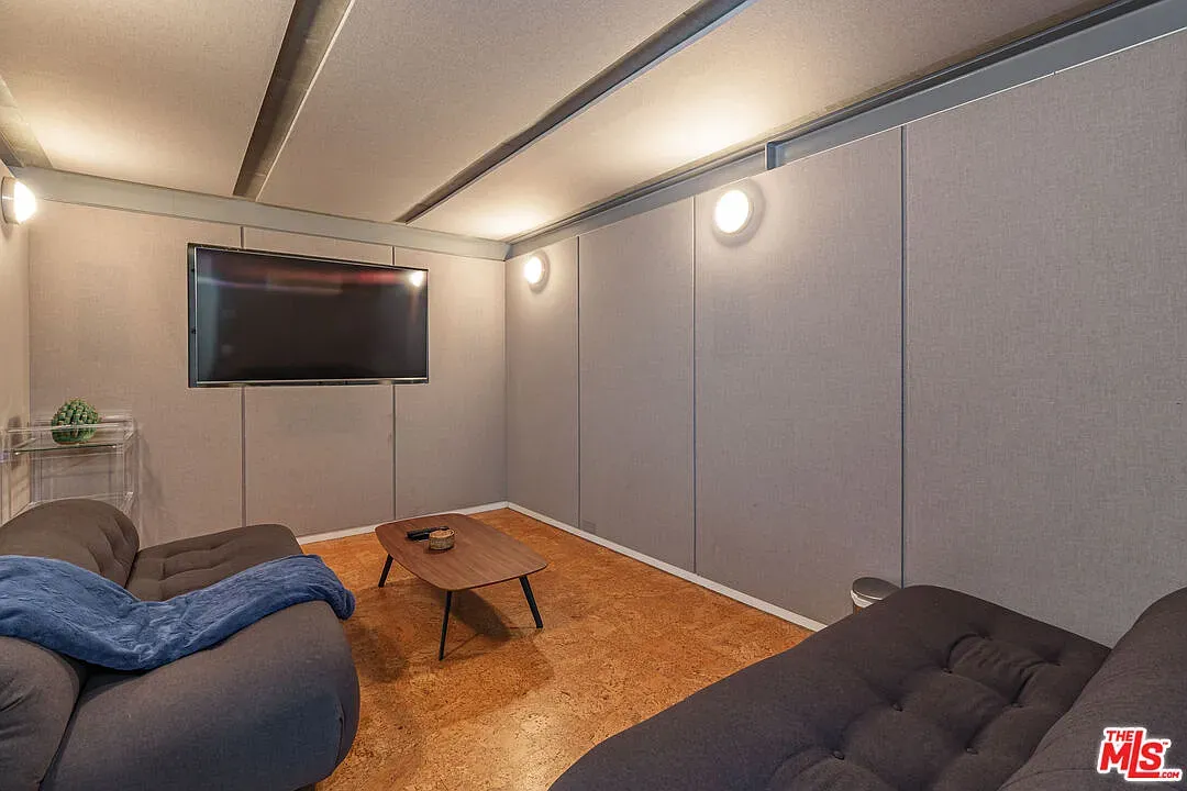 Media room with those soft wall panels and metallic ceiling beams. Looks comfy.