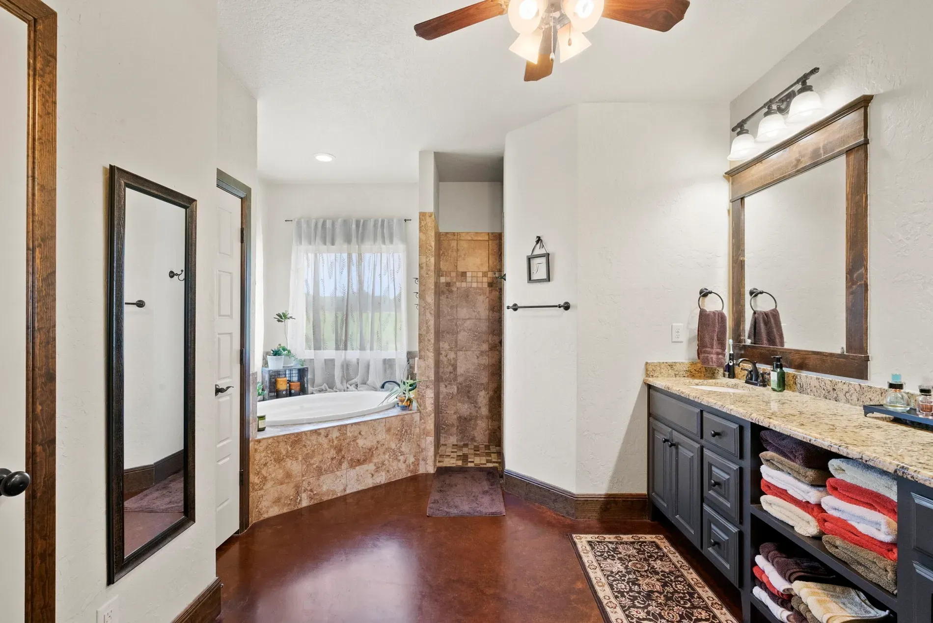 Soaking tub under the window. Neutral colors, wood accents, very calm morning routine.