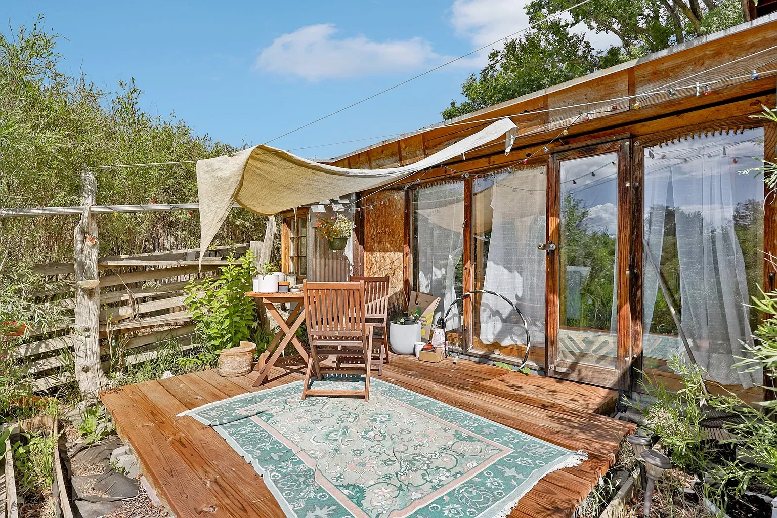 Big deck moment, boho rug, warm siding, ready for barefoot dinners.