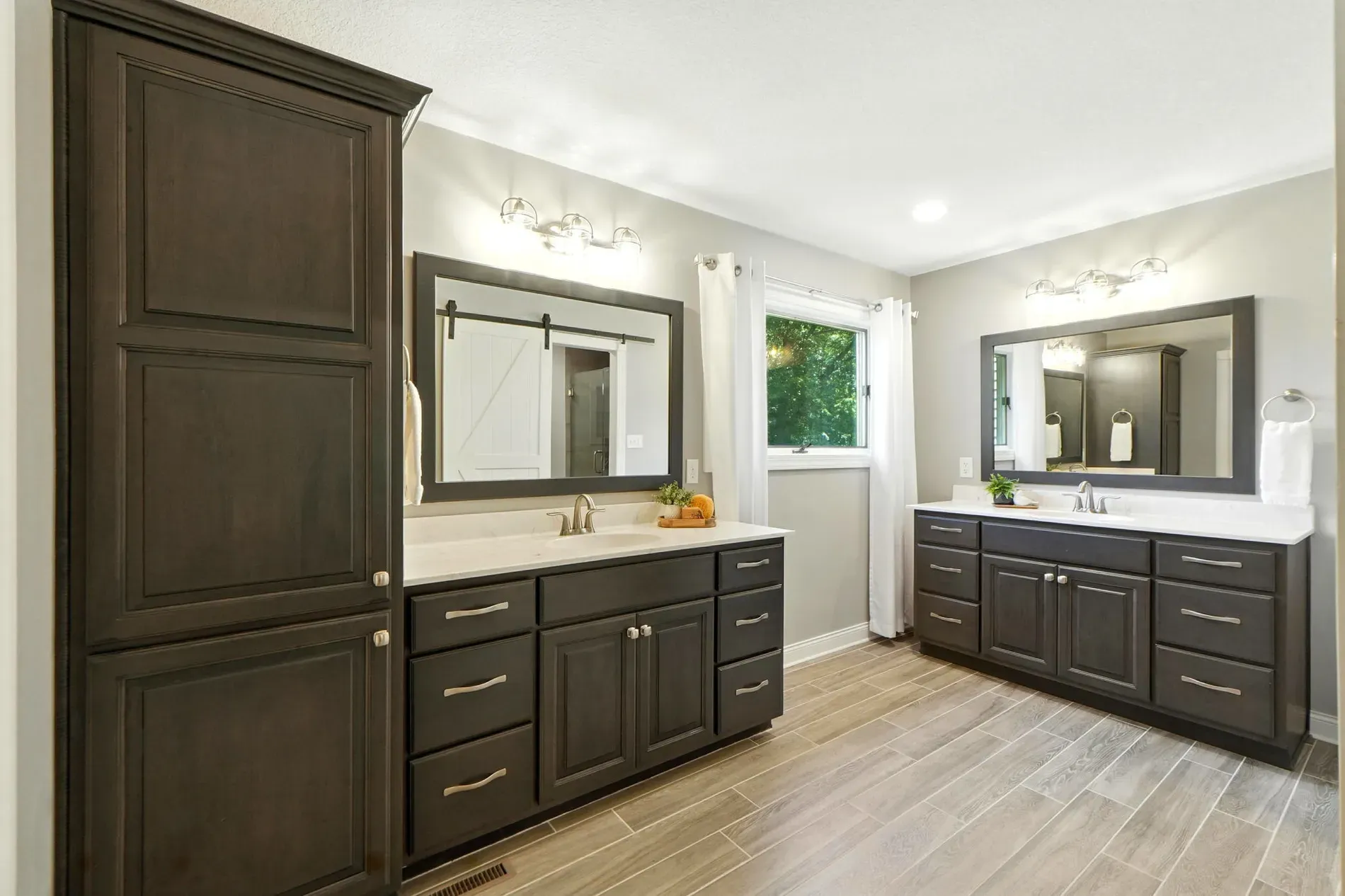 Bathroom’s calm gray with dark vanity. Big mirror helps. Shower looks standard?