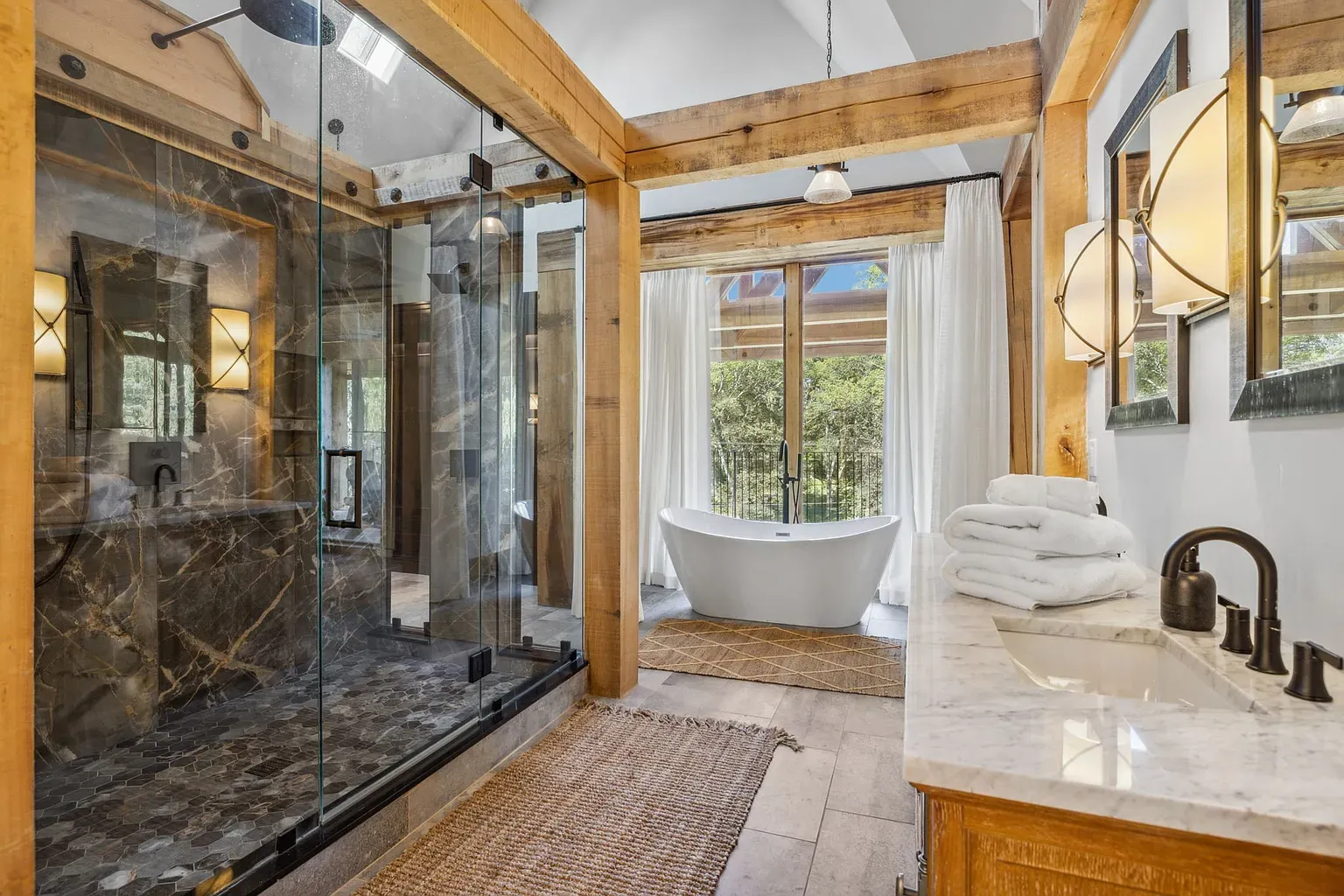 That shower is basically a cave spa. Dark stone, glass, warm wood everywhere.