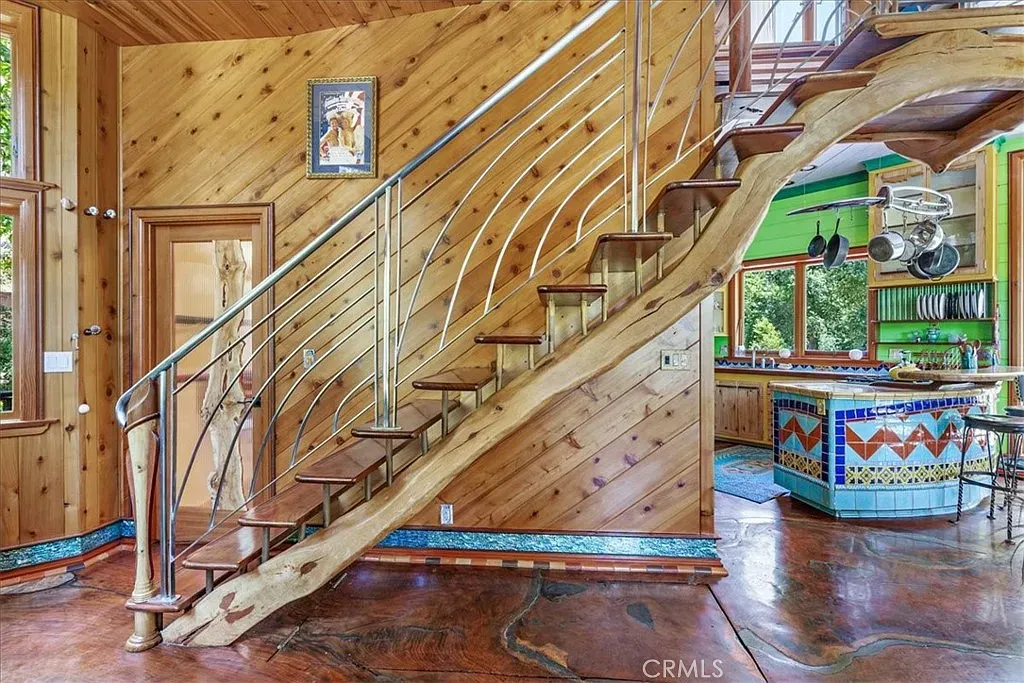 Warm wood everywhere, then that bold staircase crashes the party.