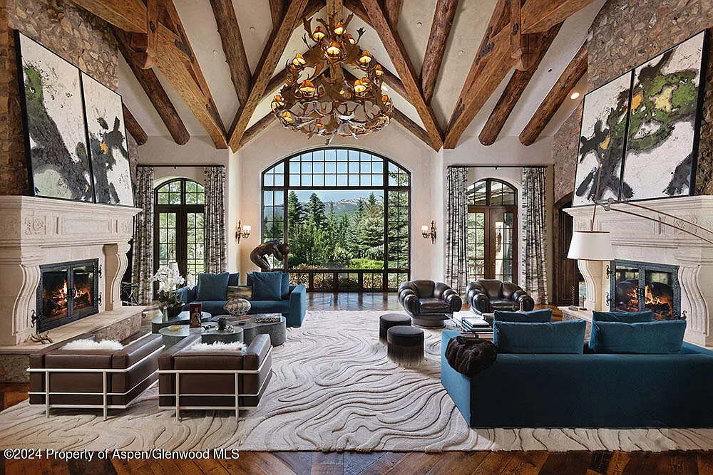 Two stone fireplaces facing off under those massive beams. Big lodge energy.