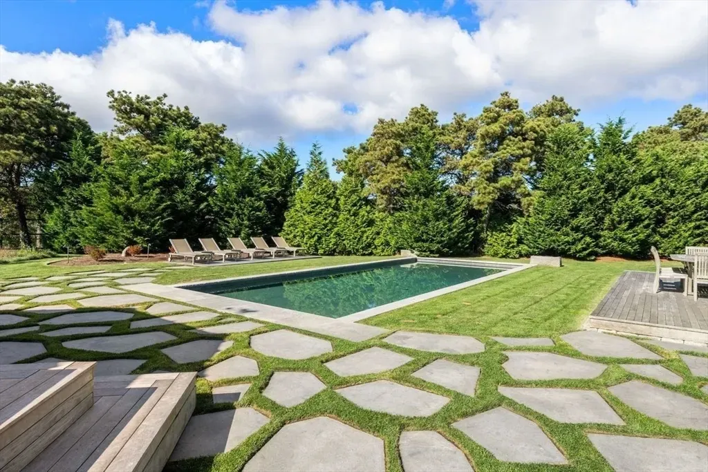 Sleek rectangle pool framed by greenery. I’d waste summers right there.