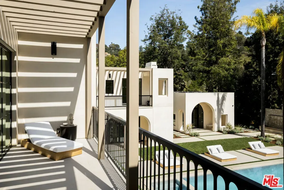 Back outside — balcony with black rails, white stucco. Simple loungers, easy life.