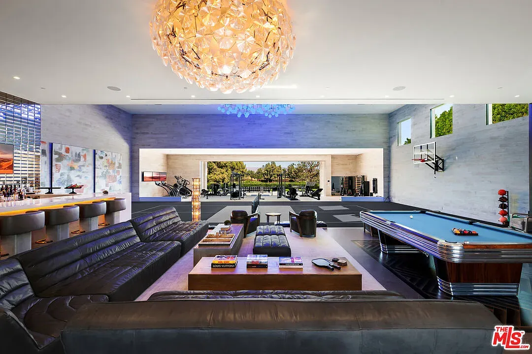 Big flex room—soft gray walls, crystal chandelier, definitely set up for hanging out.