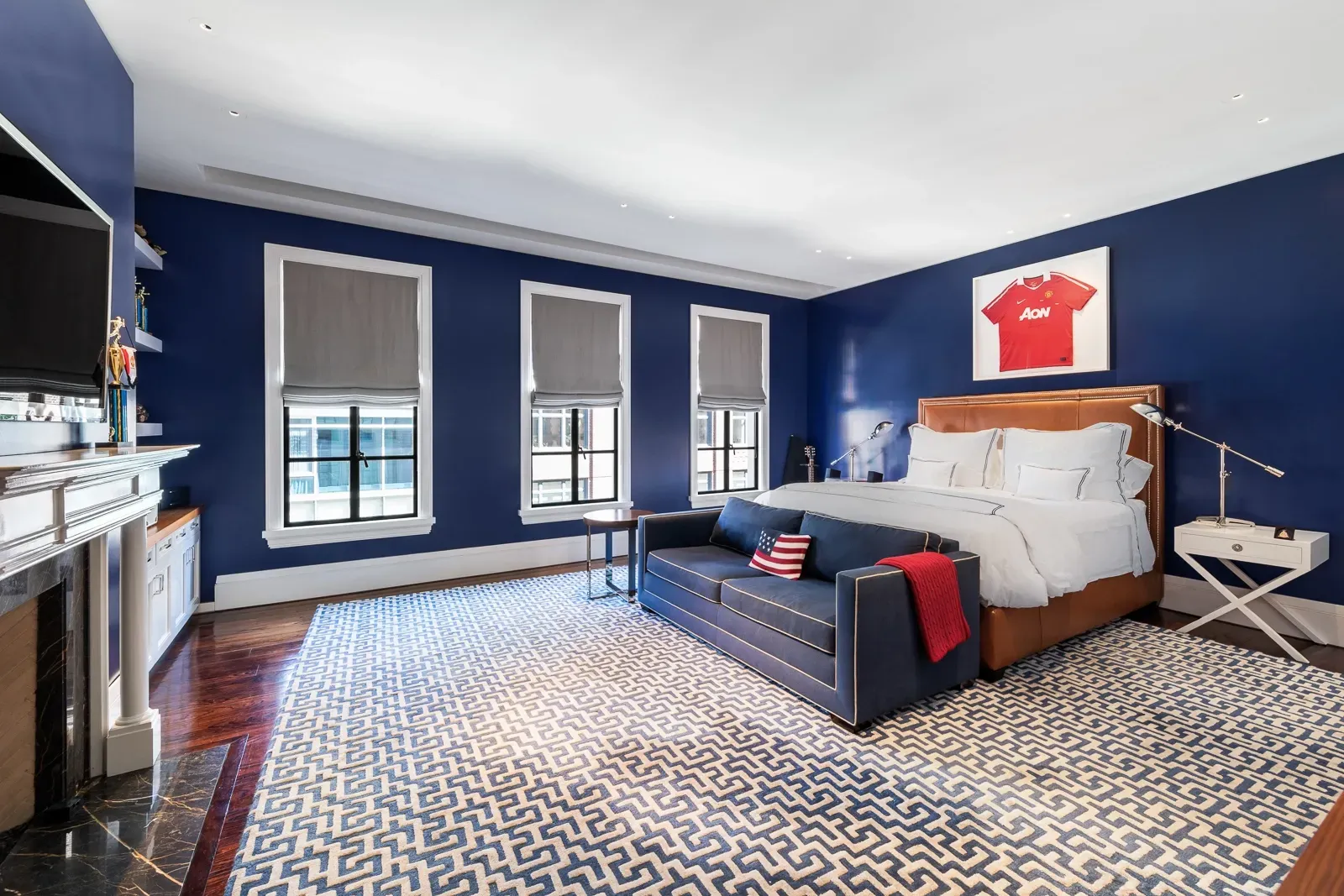 Navy walls with a leather headboard. White sheets pop hard.