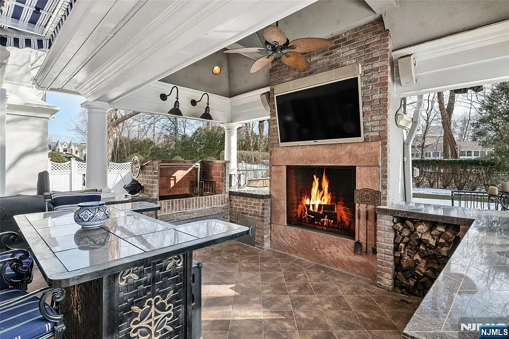 Stone fireplace on the patio. TV above—cozy or risky?