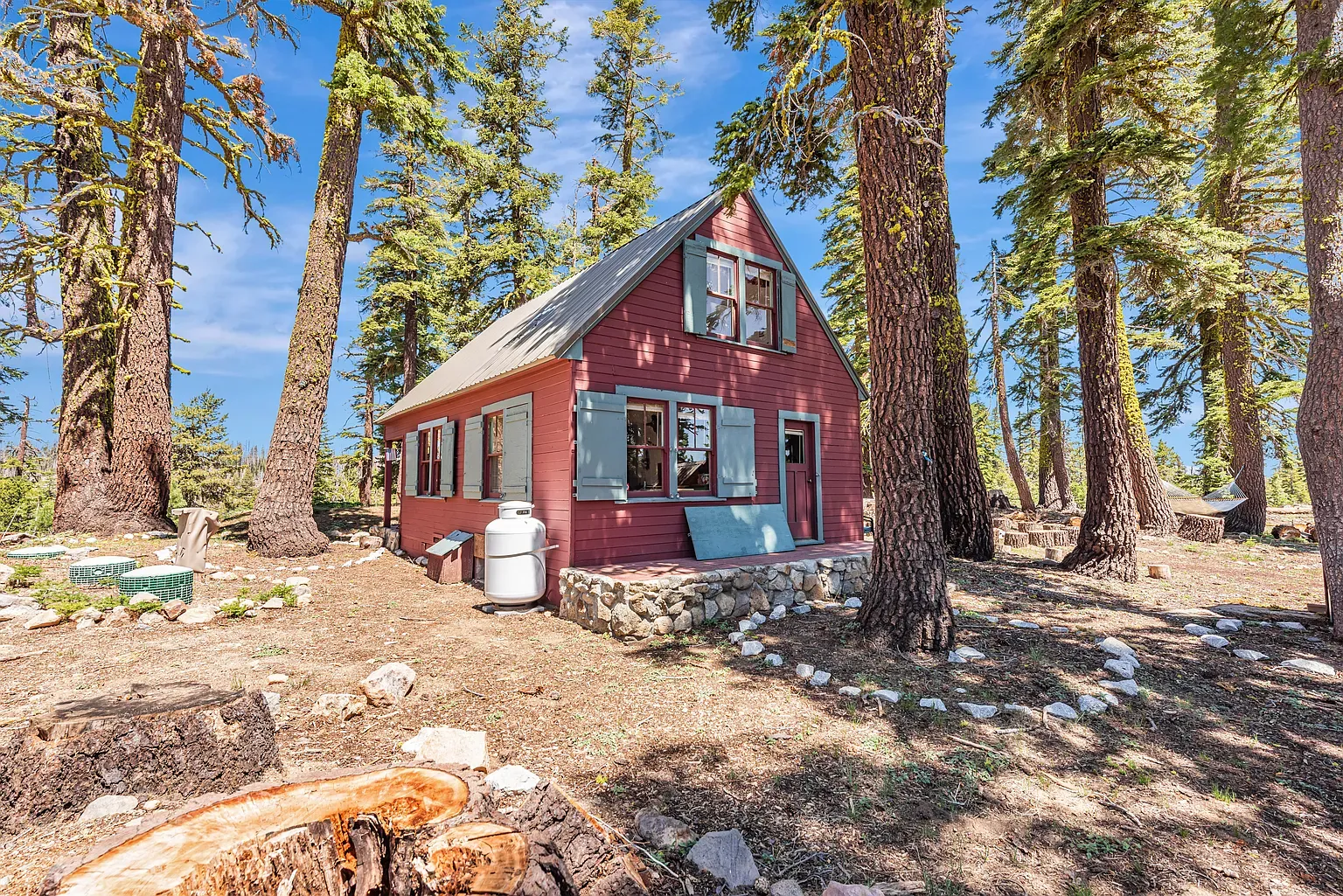 Another angle. red siding, white trim, pines everywhere. Feels private without being remote.