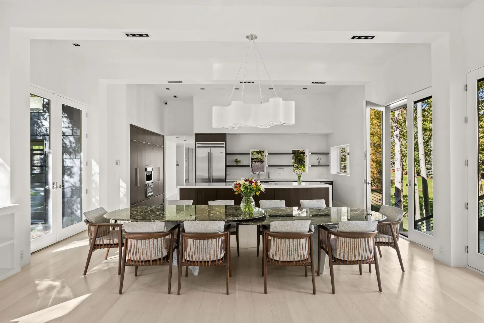 Long granite table is dramatic. Woven chairs soften it. Anyone else hungry?